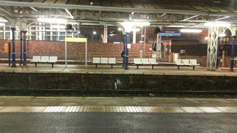 An Empty Train Station At Night With Benches On The Platform