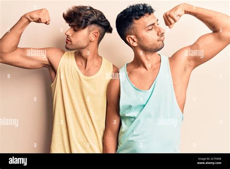 Jeune gay couple portant des vêtements décontractés montrant les bras muscles souriant fier