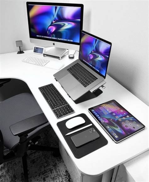 A White Desk Topped With Two Laptops Next To A Desktop Computer And