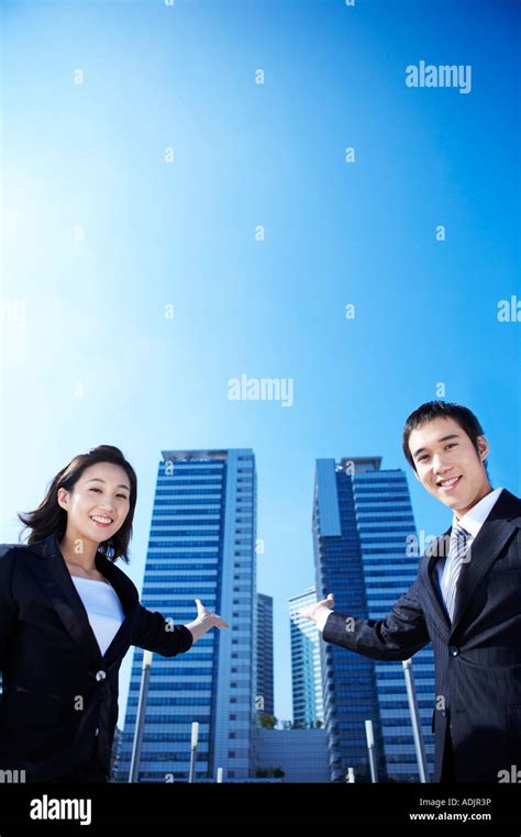 A Businessman And A Businesswoman Showing A Building With A Smile Stock