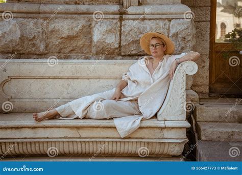 Une Belle Femme Mature Assise Sur Un Banc En Pierre Dans Un Chapeau Et Repose Image Stock