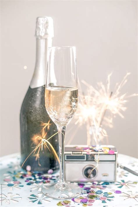 A Bottle Of Champagne And Two Glasses On A Table With Confetti