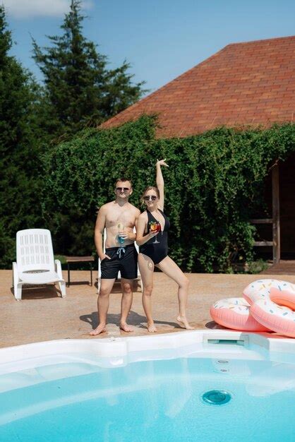 Cara e uma garota em trajes de banho estão relaxando perto da piscina