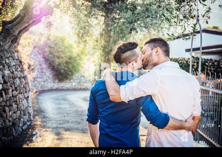 Vue arrière des hommes gay s embrasser tout en étant assis sur la rivière par un mur de
