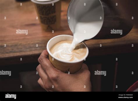 Cropped Image Of Hand Pouring Milk In Coffee Stock Photo Alamy