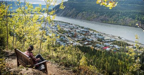 a person sitting on a bench overlooking a river and town in the ...