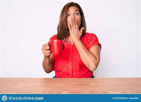 Middle Age Brunette Woman Drinking A Cup Of Coffee Sitting On The Table