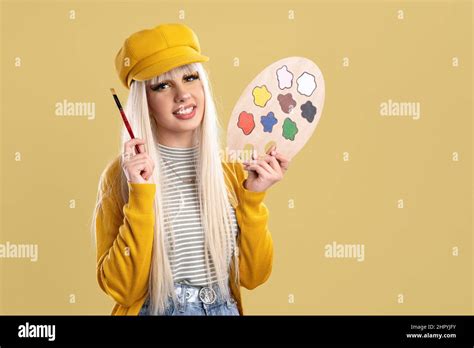 Blonde Spanish Woman With Cap And Paint Palette On A Yellow Background With A Smiling Face Stock