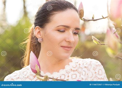 Closeup Portrait Of Amazing Brunette Model With Nude Makeup Posing Near The Blooming Magnolia