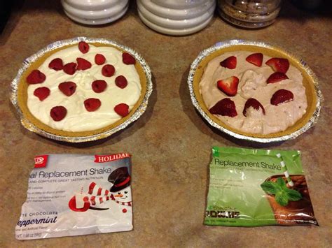 Two Pies Sitting On Top Of A Counter Covered In Frosting And Strawberries