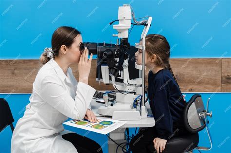 Детский офтальмолог с щелевой лампой осматривает глаза и роговицу ...