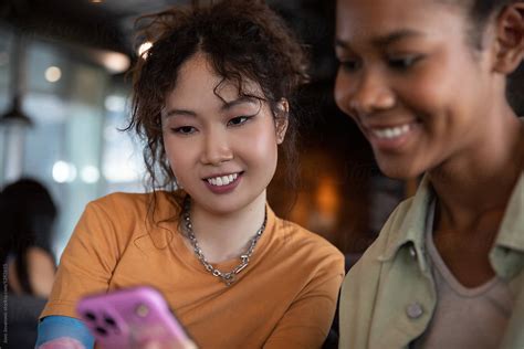 Smiling Woman Sharing Mobile Phone Content With Her Friend Stock