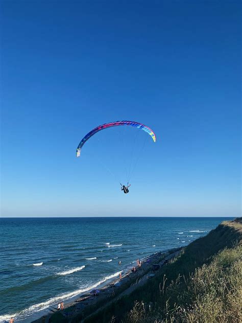 Anonymous person flying on paraglider over beach · Free Stock Photo