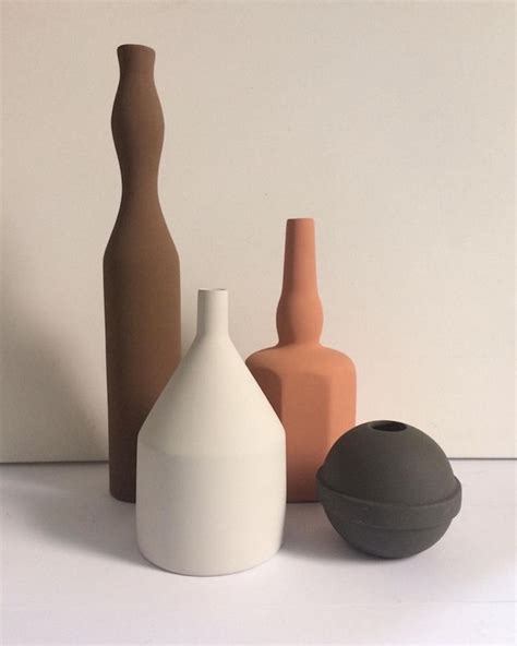 Three Different Colored Vases Sitting Next To Each Other On A White