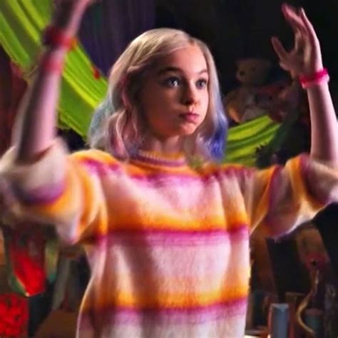 A Woman With Blonde Hair Wearing A Colorful Sweater And Holding Her