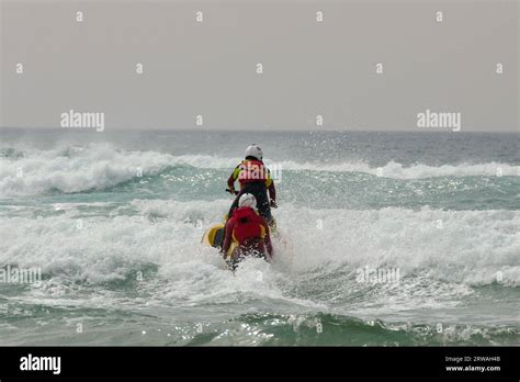 RNLI Lifeguard Member On Jet Ski With Another On A Rescue Sled Heading