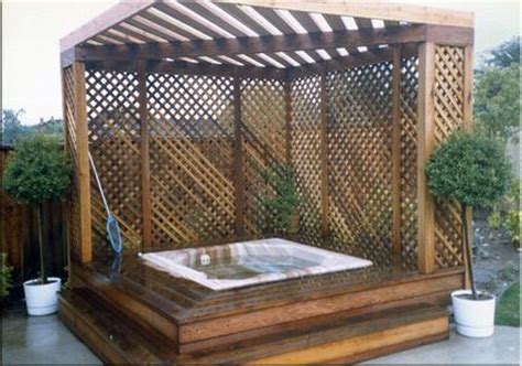 A Hot Tub Sitting On Top Of A Wooden Deck Next To A Fence And Potted Plants