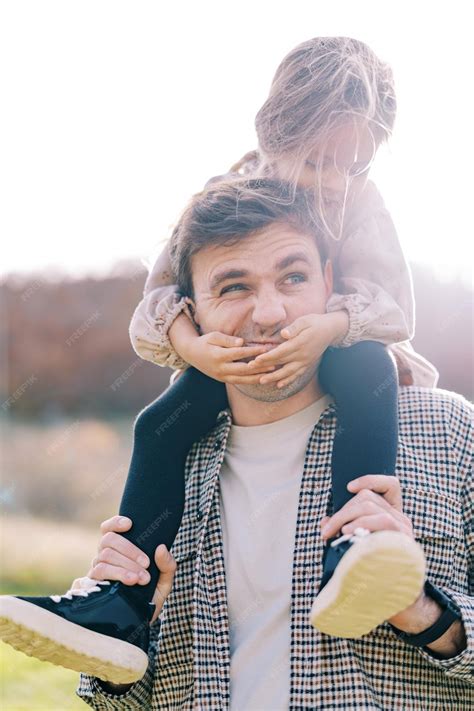 Premium Photo Little Smiling Girl Covered Her Dad Mouth With Her Palms While Sitting On His