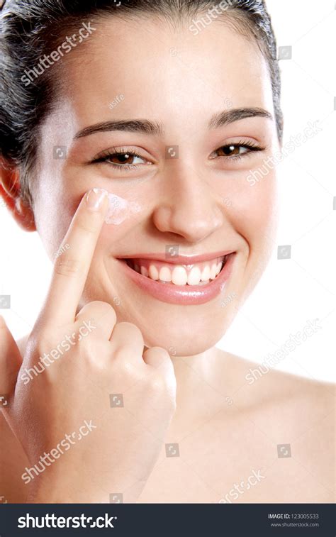 Beautiful And Happy Girl Applying Moisturizing Cream On Her Cheek