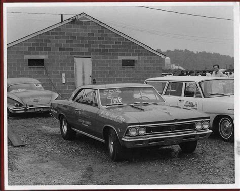 An Old Black And White Photo Of Some Cars Parked In Front Of A Brick