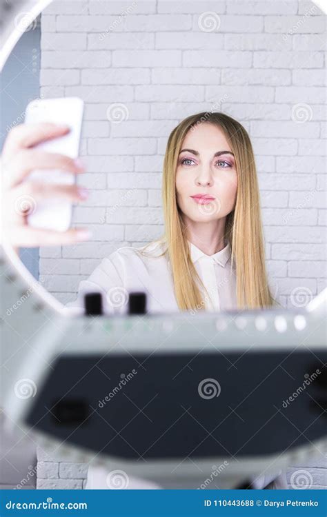 Young And Beautiful Woman Taking Selfie With Mobile Phone In Light Of