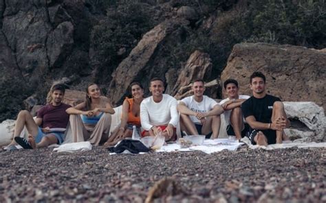 A Group Of People Sitting Next To Each Other On A Rocky Beach With