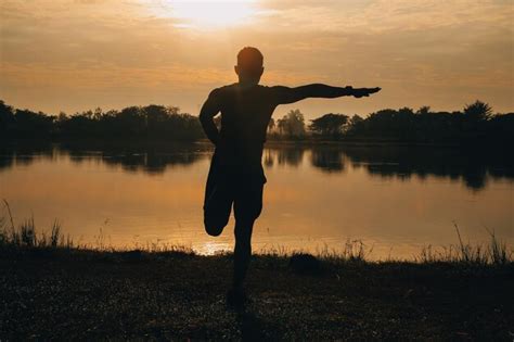 Silueta De Un Corredor Corriendo En La Playa Al Atardecer Con El Sol En