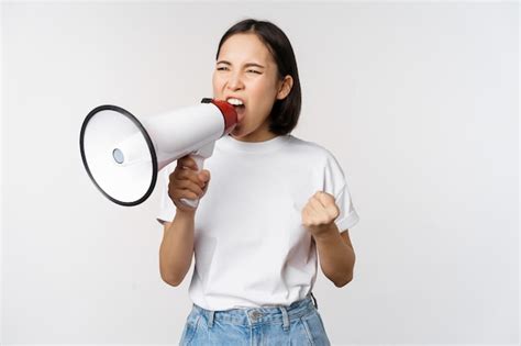 Mulher asiática confiante gritando no megafone gritando e protestando