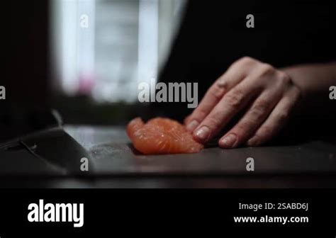 Close Up Of Hands Slicing Fresh Salmon Fillet On A Dark Background