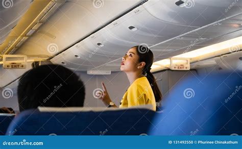 A Female Flight Attendants On The Aisle Show Passengers About Safety