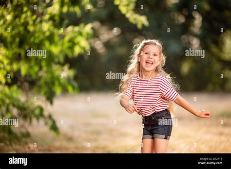 Bonne petite fille blonde écoutant de la musique avec des écouteurs