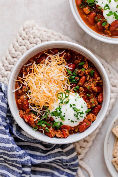 Single Serving Of Turkey Chili In A White Bowl Garnished With Sour