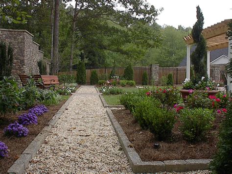 a garden with flowers and trees in the background, along with a walkway ...