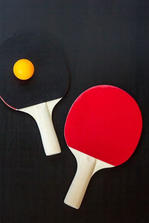 Raquetes de tênis de mesa ou ping pong e bola em um fundo preto Foto