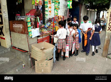 Indian school children in uniform gather around a small shop on the street to buy treats before ...