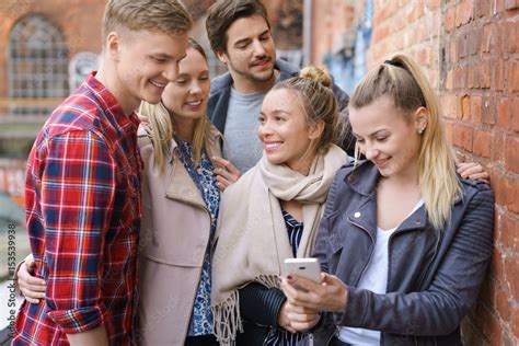 Freunde Treffen Sich In Der Stadt Und Schauen Auf Ein Handy Stock Foto