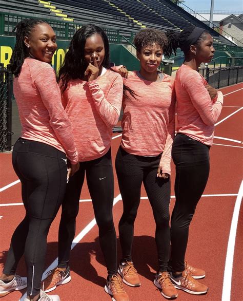 Four Women In Pink Shirts And Black Pants Standing On A Tennis Court