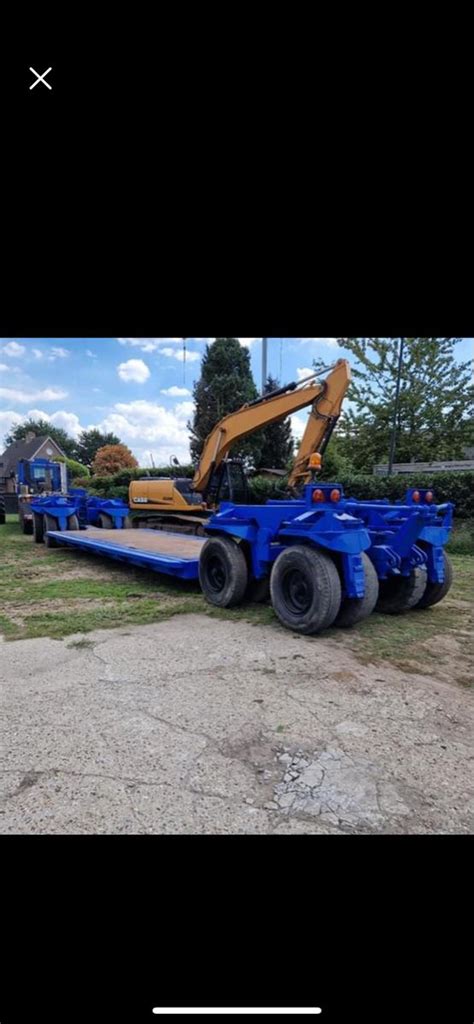 The Back End Of A Blue Trailer Parked On Top Of A Dirt Field