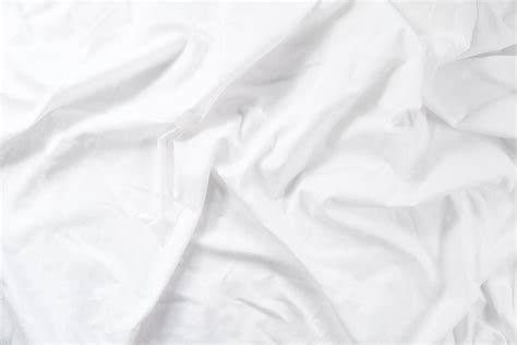 Crumpled sheet. Morning bed. White fabric texture.