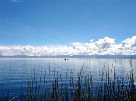 A Boat Floating On Top Of A Large Body Of Water Under A Cloudy Blue Sky