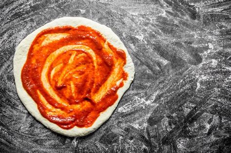 Premium Photo Raw Pizza Rolled Out Dough With Tomato Paste