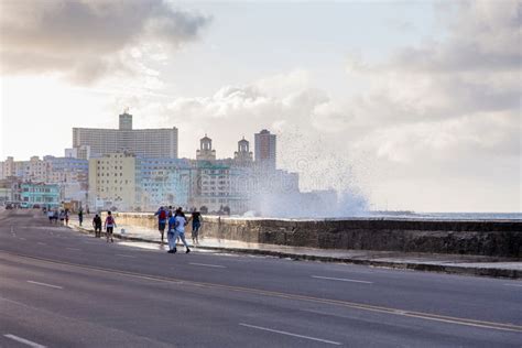 People Walking Along The Malecon Being Sprayed By Wave Crashing Against