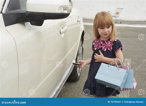 La Petite Fille Avec Des Paquets S Approchent De La Voiture Image Stock