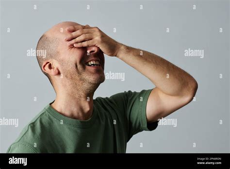 Candid Portrait Of Mature Bald Man Laughing Emotionally With Eyes Closed Against Pale Grey