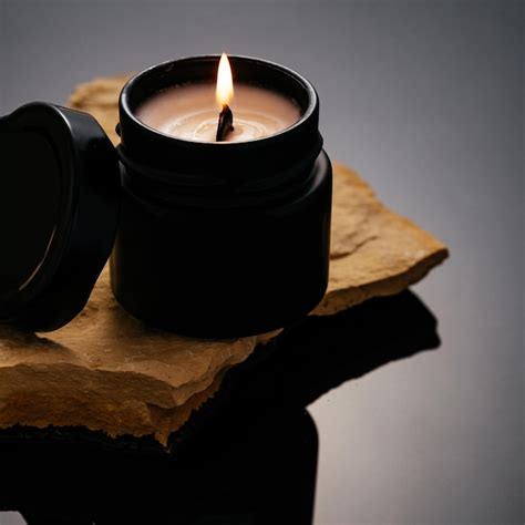 Premium Photo A Candle In A Black Jar Stands On A Stone In The Water