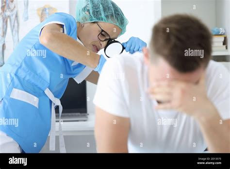 El médico con lupa en la mano examina el recto de hombre paciente