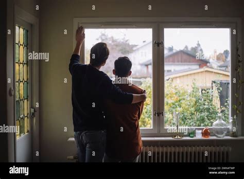 Rear View Of Man With Arm Around Gay Couple Looking Through Window At Home Stock Photo Alamy