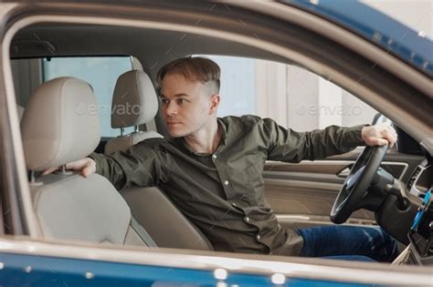 Man Is Sitting In A Blue Car In A Car Dealership A Man Buys A Car At A