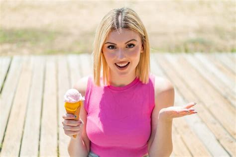 Une Jeune Jolie Femme Blonde Avec Une Crème Glacée Au Cornet à L extérieur Avec Une Expression
