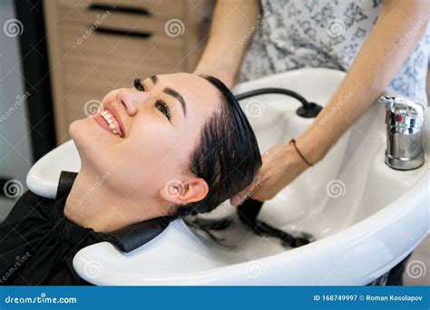 Woman Getting Hair Treatment In A Spa Salon Using Shampoo For Hair